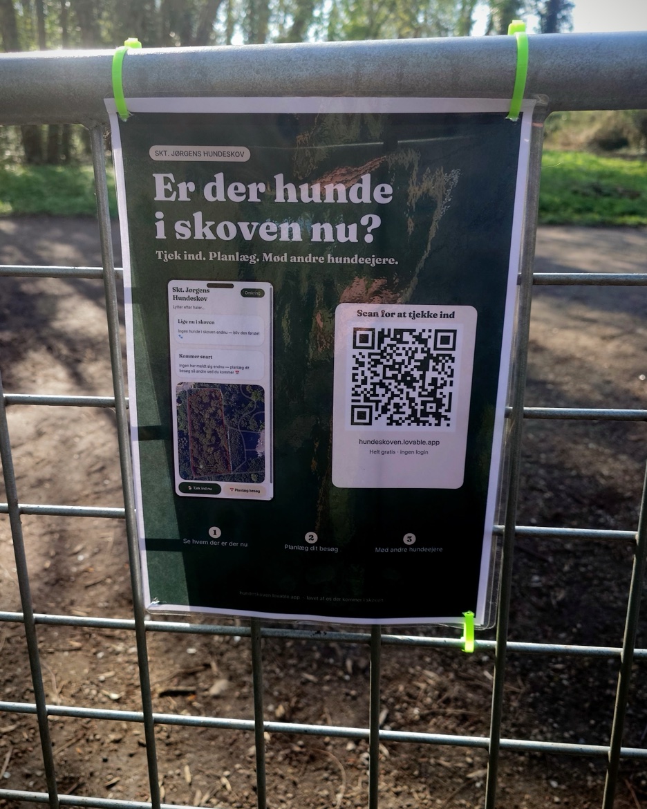 Den laminerede plakat for Hundeskoven-appen lynlåst fast på lågen til Skt. Jørgens Hundeskov